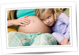A little girl listening to her pregnant mother's stomach.